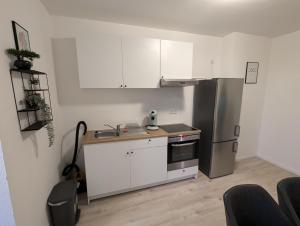 a kitchen with white cabinets and a stainless steel refrigerator at Moderne Wohnung im Erdgeschoss mit Terrasse I ruhige Umgebung in Bremerhaven
