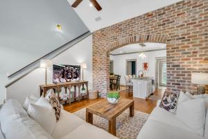 a living room with a white couch and a brick wall at Cowbell Cottage in Starkville