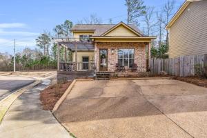 a brick house with a porch and a driveway at Cowbell Cottage in Starkville