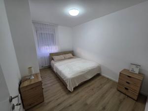 a white bedroom with a bed and a wooden floor at Relje krilatice in Novi Pazar