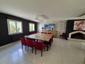 una sala da pranzo con tavolo in legno e sedie rosse di Maison de la villa à la fosse à l'âne 5 chambres a Le Fuilet