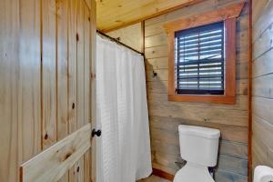 a bathroom with a toilet and a window at Modern and Cozy 5BR Family Cabin with Private Pool, Hot Tub, Pool Table, Fire Pit & Cozy Mountain Vibes in Sevierville