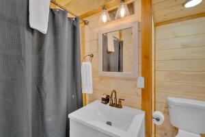 a bathroom with a sink and a toilet and a mirror at Modern and Cozy 5BR Family Cabin with Private Pool, Hot Tub, Pool Table, Fire Pit & Cozy Mountain Vibes in Sevierville