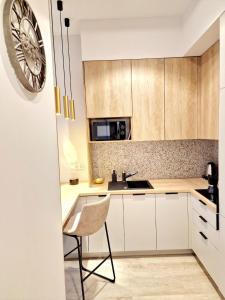 a kitchen with white cabinets and a chair and a clock at Hanza Tower 615 in Szczecin