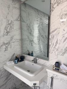 a white bathroom with a sink and a mirror at Oyster court gulberg in Lahore