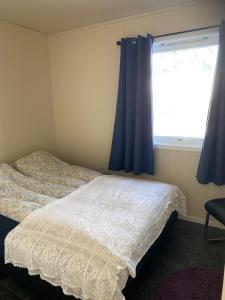 a bedroom with a bed and a window with blue curtains at House in Vågan in Hopen