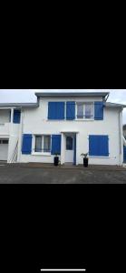 a white house with blue windows and blue doors at Appartement bord de mer in Jullouville-les-Pins