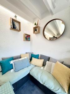 een woonkamer met een bank met kussens en een spiegel bij Maisonnette de charme Bord de mer Piscine in Guidel