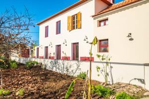 a white house with red windows and a fence at Casa os Gauleses in Gaula