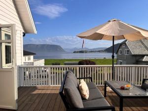a porch with a couch and an umbrella and a table at Cozy house with sea view close to Ålesund in Ålesund