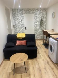 un salon avec un canapé noir et une table dans l'établissement Le lodge, à Dole