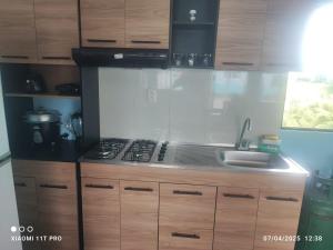 a kitchen with wooden cabinets and a stove and a sink at alojamiento campestre DESCANSO TOTAL in Filandia