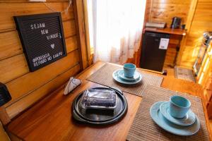 a table with two cups and a cell phone on it at Chalé alecrim Rancho Queimado in Aguas Mornas