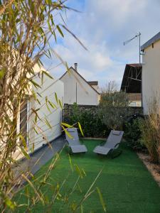 une cour avec 2 chaises longues sur la pelouse dans l'établissement Le Cocon de Marine, à Triel-sur-Seine