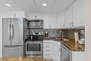 a kitchen with white cabinets and a stainless steel refrigerator at Paradise Towers #104 in Carolina Beach