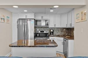 a kitchen with white cabinets and a stainless steel refrigerator at Paradise Towers #104 in Carolina Beach