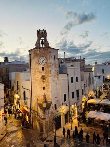 a group of people walking in a street with a clock tower at L&S Rooms in Monopoli
