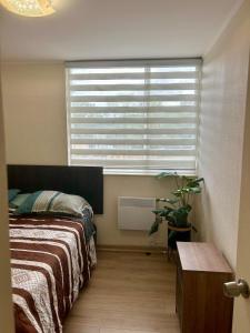 a bedroom with a bed and a large window at Amplio departamento in Temuco
