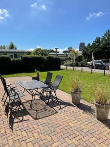 a picnic table and chairs on a brick patio at Cozy chalet near beach, dune and forest in Goedereede