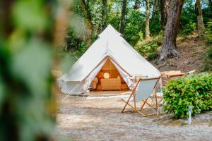 a white tent with a chair in front of it at Cocooning Tipi - Azur in Azur