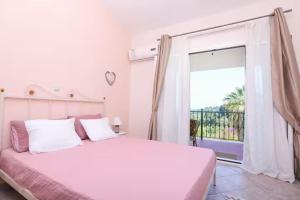 a white bedroom with a bed and a large window at Maison See View in Kontokali