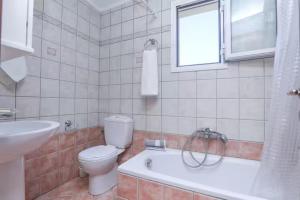 a bathroom with a toilet and a sink and a tub at Maison See View in Kontokali +12 photos