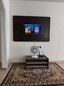 a room with a fan and a tv on a wall at Casa do Marcus in Barra do Garças