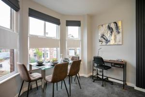 a dining room with a table and chairs and windows at Entire Luxurious 2 Bedroom Flat in Leicester