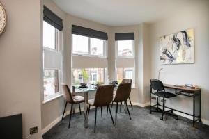 a dining room with a table and chairs and windows at Entire Luxurious 2 Bedroom Flat in Leicester