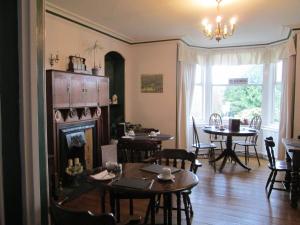 a living room with a fireplace and tables and chairs at Brooklands Guest House in Bowness-on-Windermere