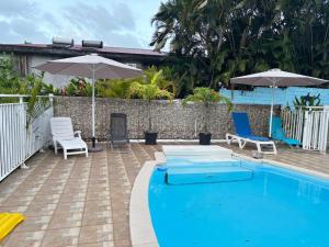 a swimming pool with chairs and umbrellas next to at Villa BEAUCI-TURLET in Goyave