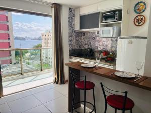 a kitchen with a counter and a large window at loft london, conforto no coração de Icarai in Niterói