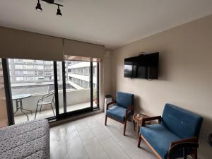 a living room with two blue chairs and a balcony at Departamento Estudio, entero in Temuco