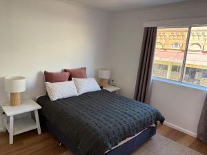 a bedroom with a bed with two tables and a window at The Nook and Cranny in Armidale