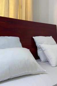 Una cama con almohadas blancas y un cabecero de madera. en Appart chic à Bonapriso, en Douala