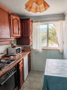 a kitchen with wooden cabinets and a microwave and a window at Apartamento con jardín in La Franca
