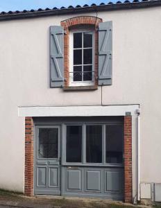 a white building with a garage and a window at Maison Cosy centre de Pouzauges in Pouzauges