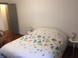 a bedroom with a white bed with colorful triangles at Maison Cosy centre de Pouzauges in Pouzauges
