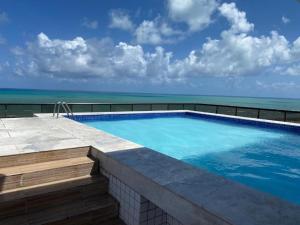 una piscina con el océano al fondo en Flat incrível em Olinda, en Olinda
