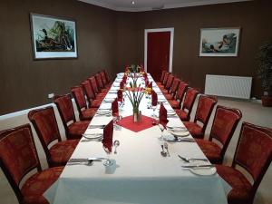 The Panmure Arms Hotel في Edzell: طاولة طويلة في غرفة مع كراسي حمراء