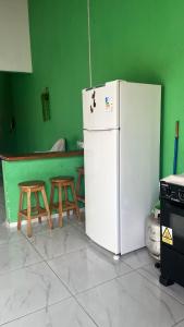 a kitchen with a white refrigerator and two stools at Rosana House Bem estar em Barreirinhas Ideal para 5 pessoas in Barreirinhas