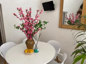 une table blanche avec un vase avec des fleurs roses sur elle dans l'établissement DIMORA MOLINI, à Monopoli