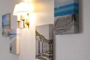 a light on a wall with two pictures of the beach at Quinta das Andorinhas in Carvoeiro