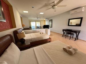 een woonkamer met 2 bedden en een piano bij HOTEL CARASOL VILLAS & SUITES in Ciudad Madero