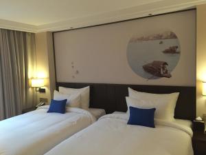 two beds in a hotel room with blue pillows at Guangzhou City Join Hotel Shipai Qiao Branch in Guangzhou