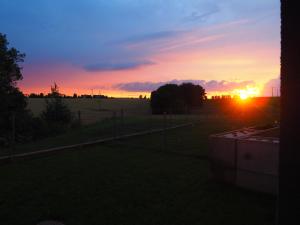 a sunset over a field with the sun setting at Serce Kotliny Kłodzkiej - Apartament 54m2 - 3 pokoje, balkon, ogródek in Kłodzko