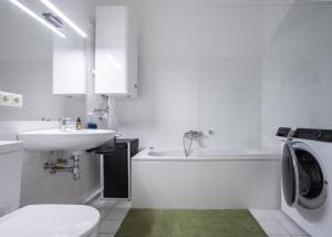 a white bathroom with a sink and a washing machine at Studio 12 in Linz