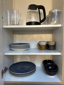 a shelf with plates and cups and a tea pot at Flamingo 2 - zentrale Wohnung - Düren in Düren - Eifel +2 photos