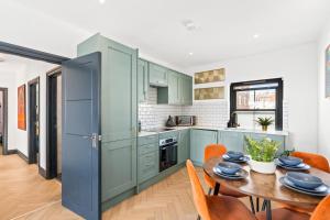 a kitchen with blue cabinets and a wooden table at Western Seaview Terrace - Central - Contractors in Brighton & Hove