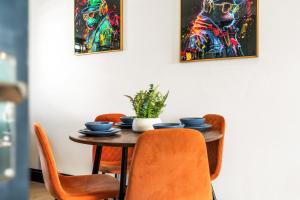 a dining room table with orange chairs and paintings on the wall at Western Seaview Terrace - Central - Contractors in Brighton & Hove +5 photos